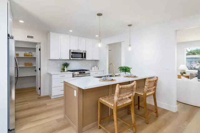 a kitchen with a dining table chairs cabinets and stainless steel appliances