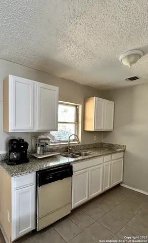a kitchen with stainless steel appliances a sink a stove and white cabinets