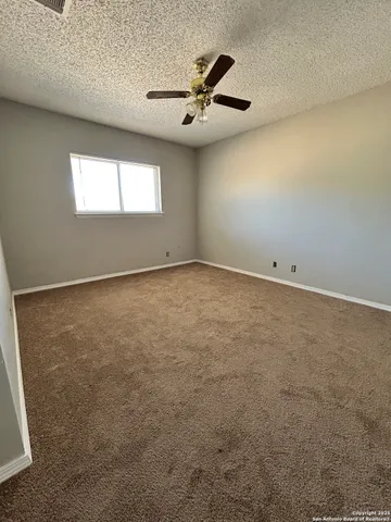 an empty room with a window and a ceiling fan