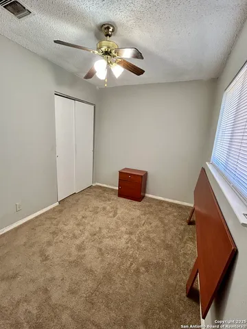 a view of an empty room with a chandelier fan