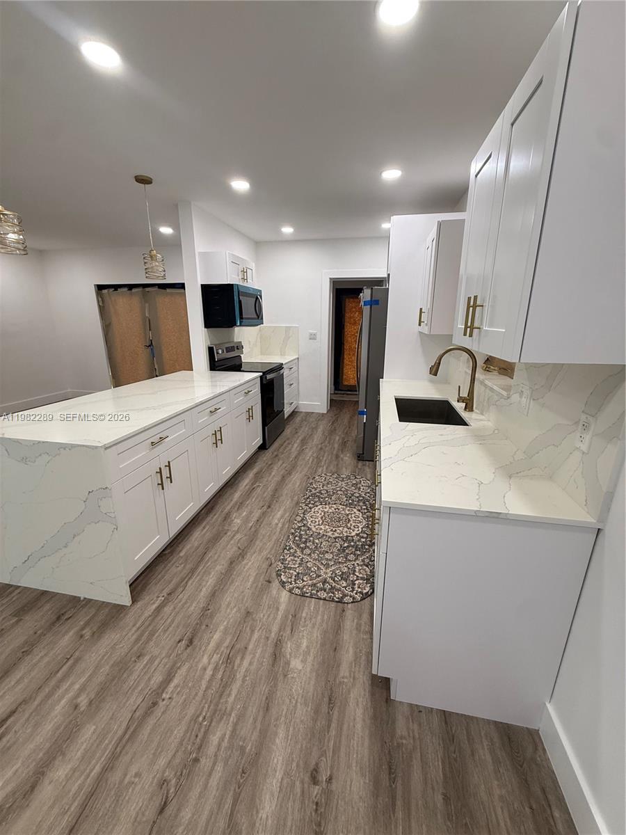 1014 West 66th Street Hialeah, FL 33012 - Photo 25 of 43 a large white kitchen with wooden floors and white stainless steel appliances