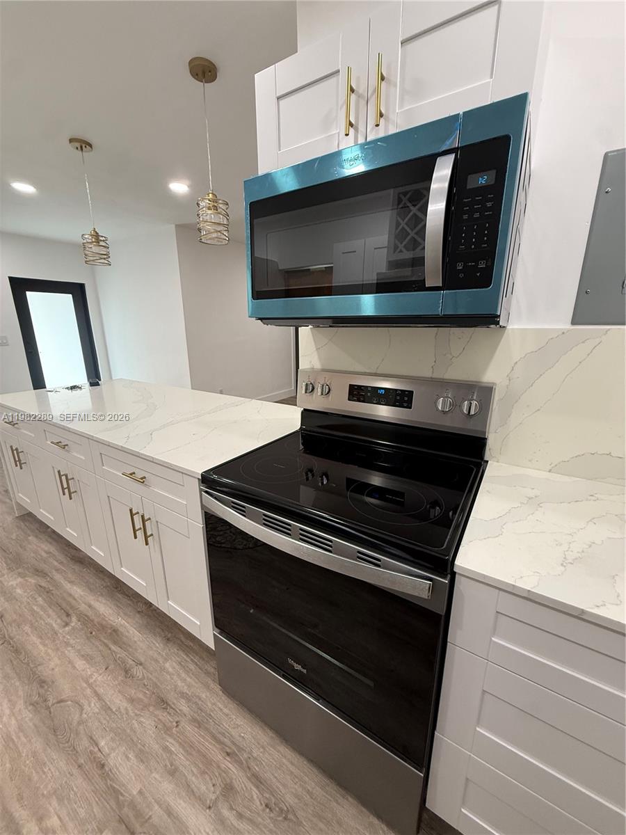 1014 West 66th Street Hialeah, FL 33012 - Photo 28 of 43 a kitchen with stainless steel appliances a stove microwave and white cabinets