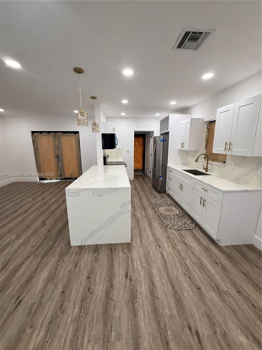 1014 West 66th Street Hialeah, FL 33012 - Photo 30 of 43 a large room with kitchen island a wooden floor appliances and a sink