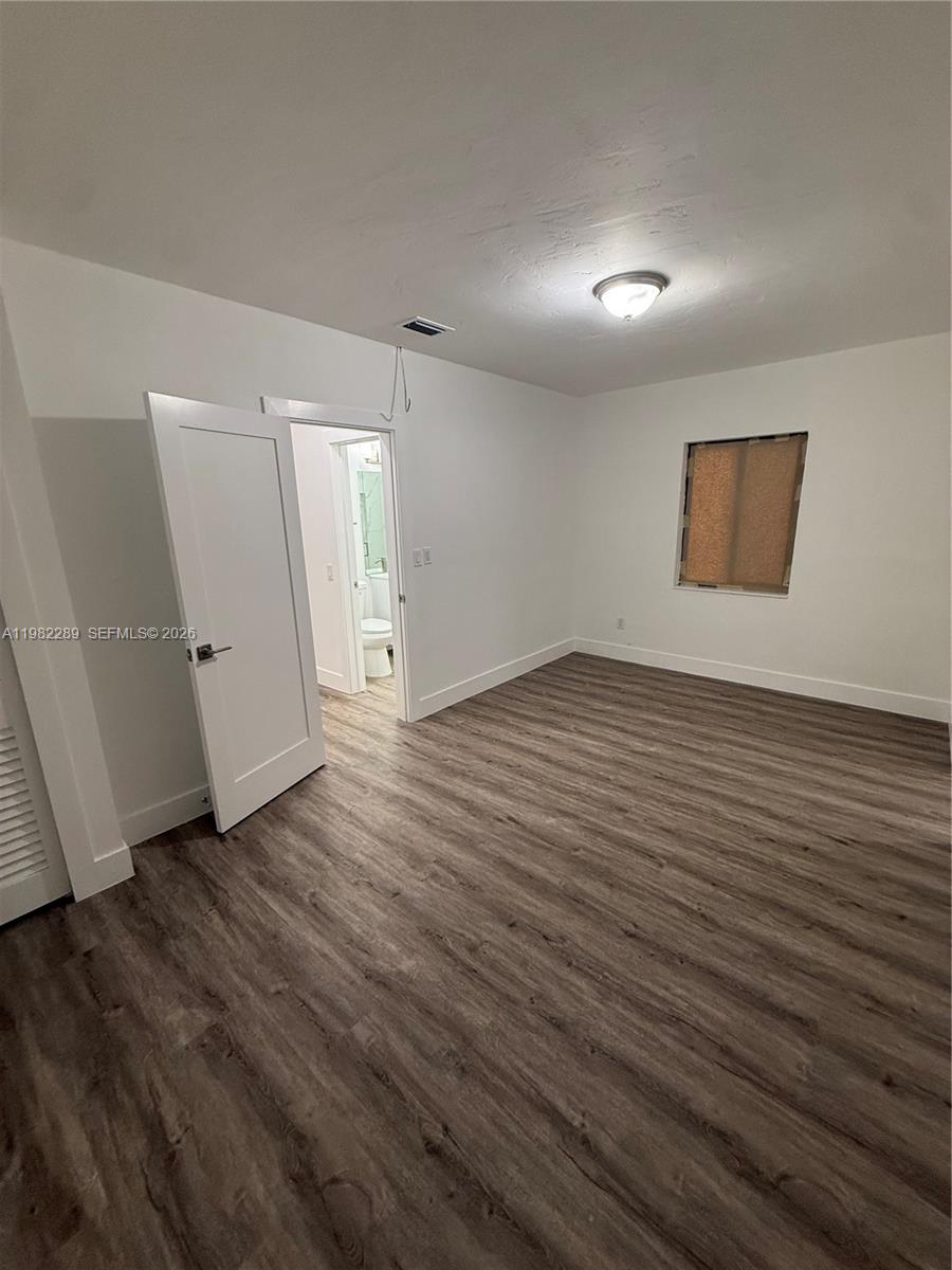 1014 West 66th Street Hialeah, FL 33012 - Photo 38 of 43 an empty room with wooden floor and white walls
