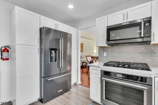 a kitchen with stainless steel appliances white cabinets and a stove a refrigerator with wooden floor