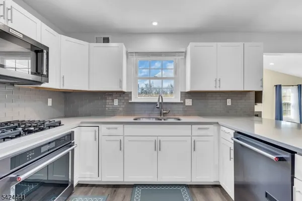 a kitchen with white cabinets appliances and a sink