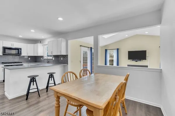 a open dining room with stainless steel appliances granite countertop a dining table chairs and granite counter top