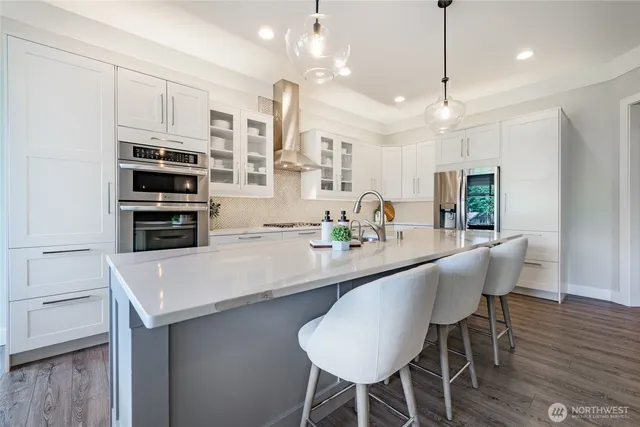 a kitchen with kitchen island a dining table chairs stainless steel appliances and cabinets