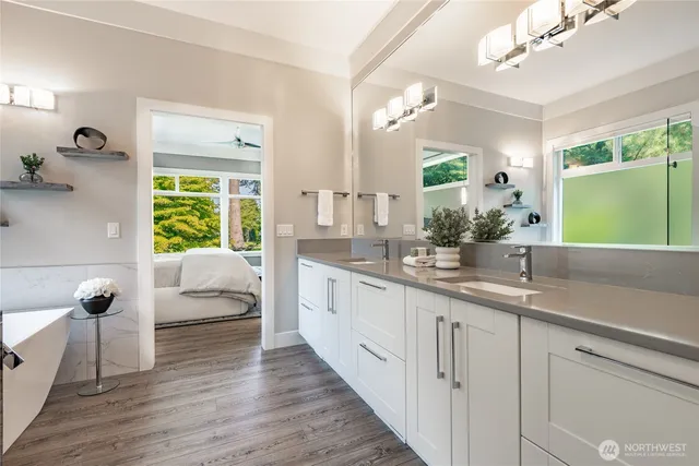 a spacious en suite bathroom with a granite countertop double vanity sink a mirror and shower