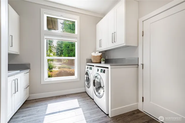 a utility room with wooden floor washer and dryer