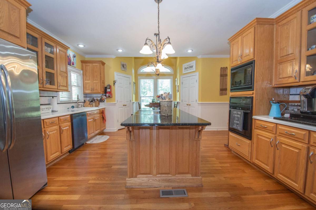 4973 Greenville Road LaGrange, GA 30241 - Photo 41 of 108 a kitchen with stainless steel appliances granite countertop a stove top oven a sink dishwasher a dining table and chairs with wooden floor