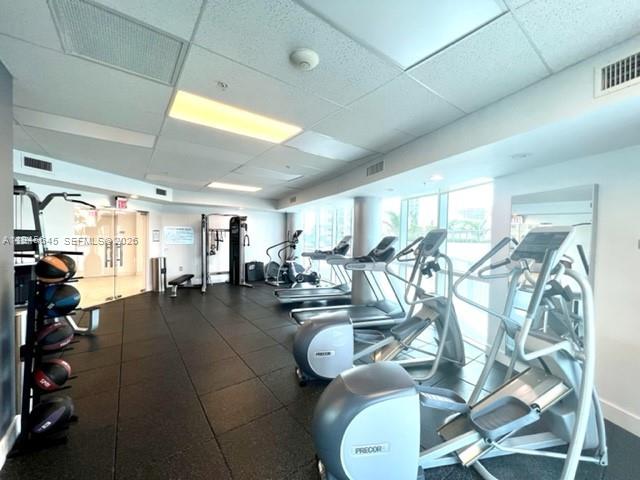 480 Northeast 30th Street, Unit 1803 Miami, FL 33137 - Photo 10 of 15 a gym room with lots of white furniture and a chandelier