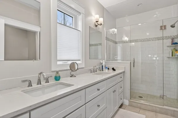 a bathroom with a double vanity sink mirror and shower