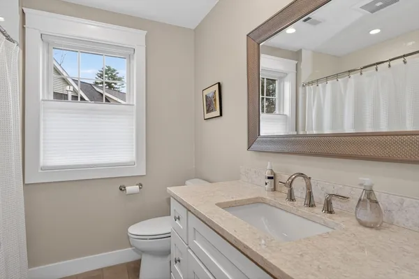 a bathroom with a granite countertop toilet sink and mirror