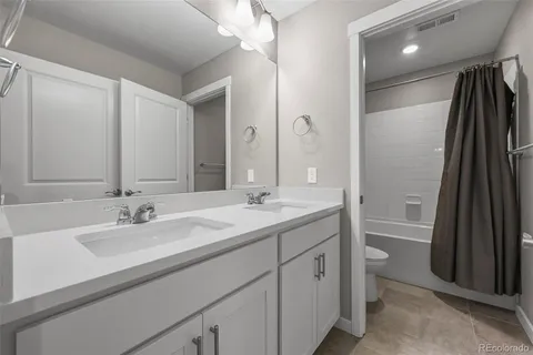 a bathroom with a double vanity sink a toilet and a mirror