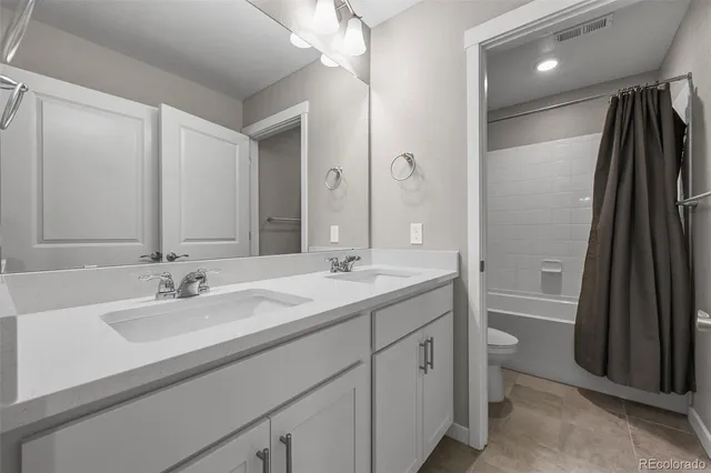 a bathroom with a double vanity sink a toilet and a mirror