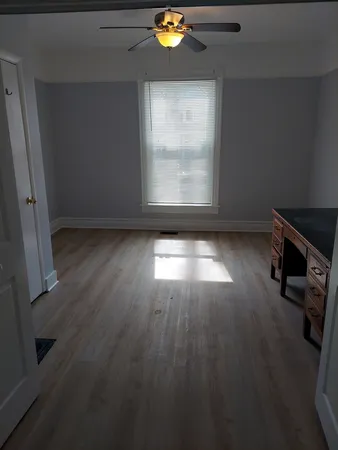 an empty room with wooden floor and windows