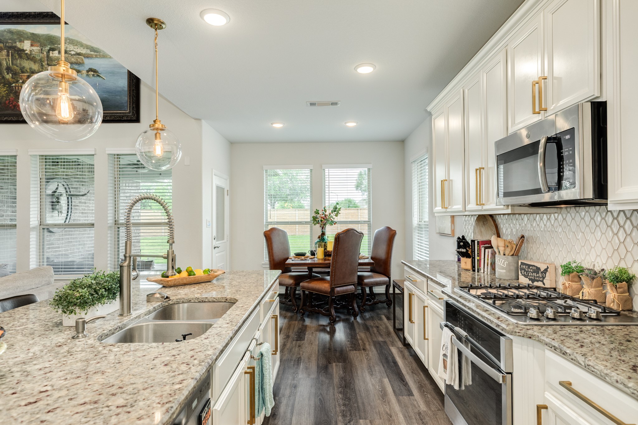 10306 Aldrin Drive Rosharon, TX 77583 - Photo 14 of 50 The kitchen features modern hardware, a gas range top, and built-in oven and microwave. In the background, the breakfast area is bathed in natural light from surrounding windows.