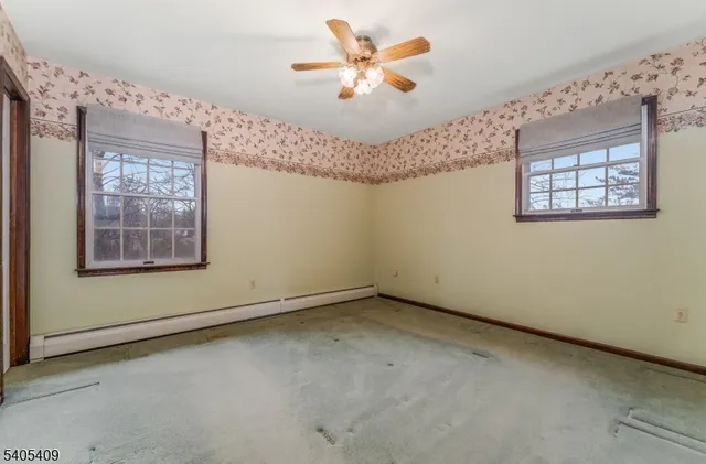 an empty room with windows and fan