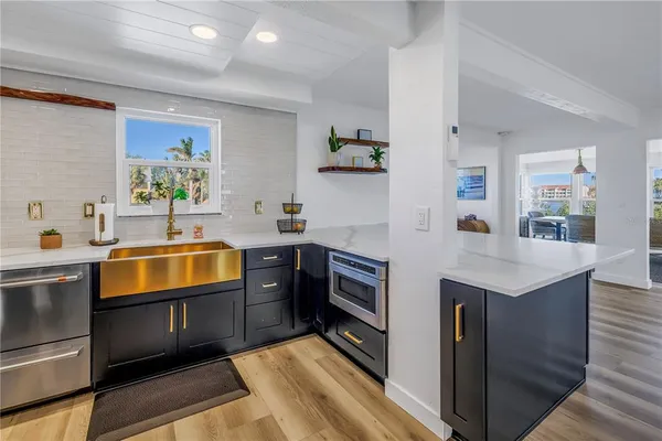 a kitchen with stainless steel appliances granite countertop a sink counter space and view of living room