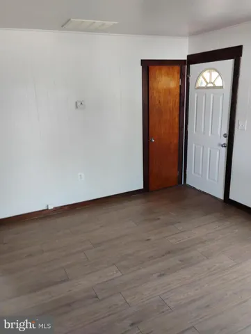 a view of an empty room with wooden floor and closet
