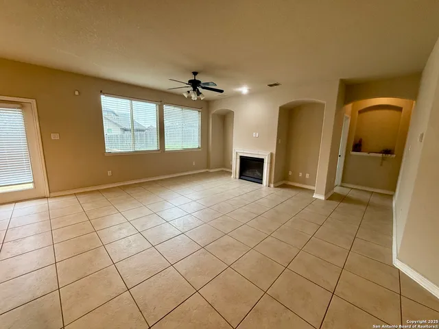 a view of an empty room with window and chandelier fan