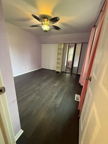 en empty room with wooden floor and fan