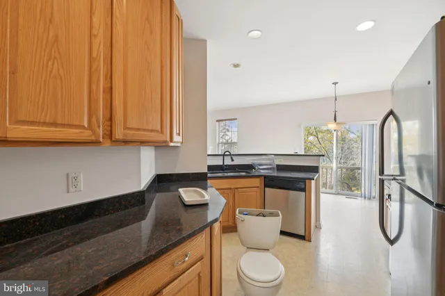 a kitchen with stainless steel appliances granite countertop a sink a stove and a wooden cabinets
