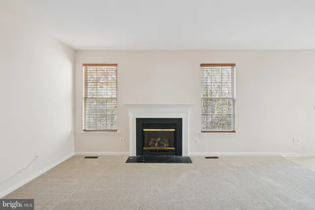 an empty room with windows and fireplace
