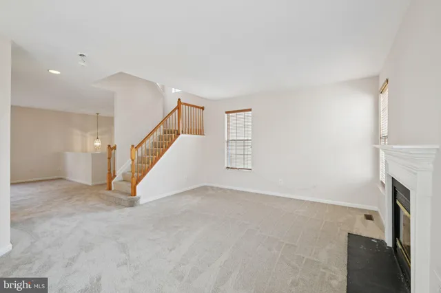 a view of an empty room with fireplace and stairs
