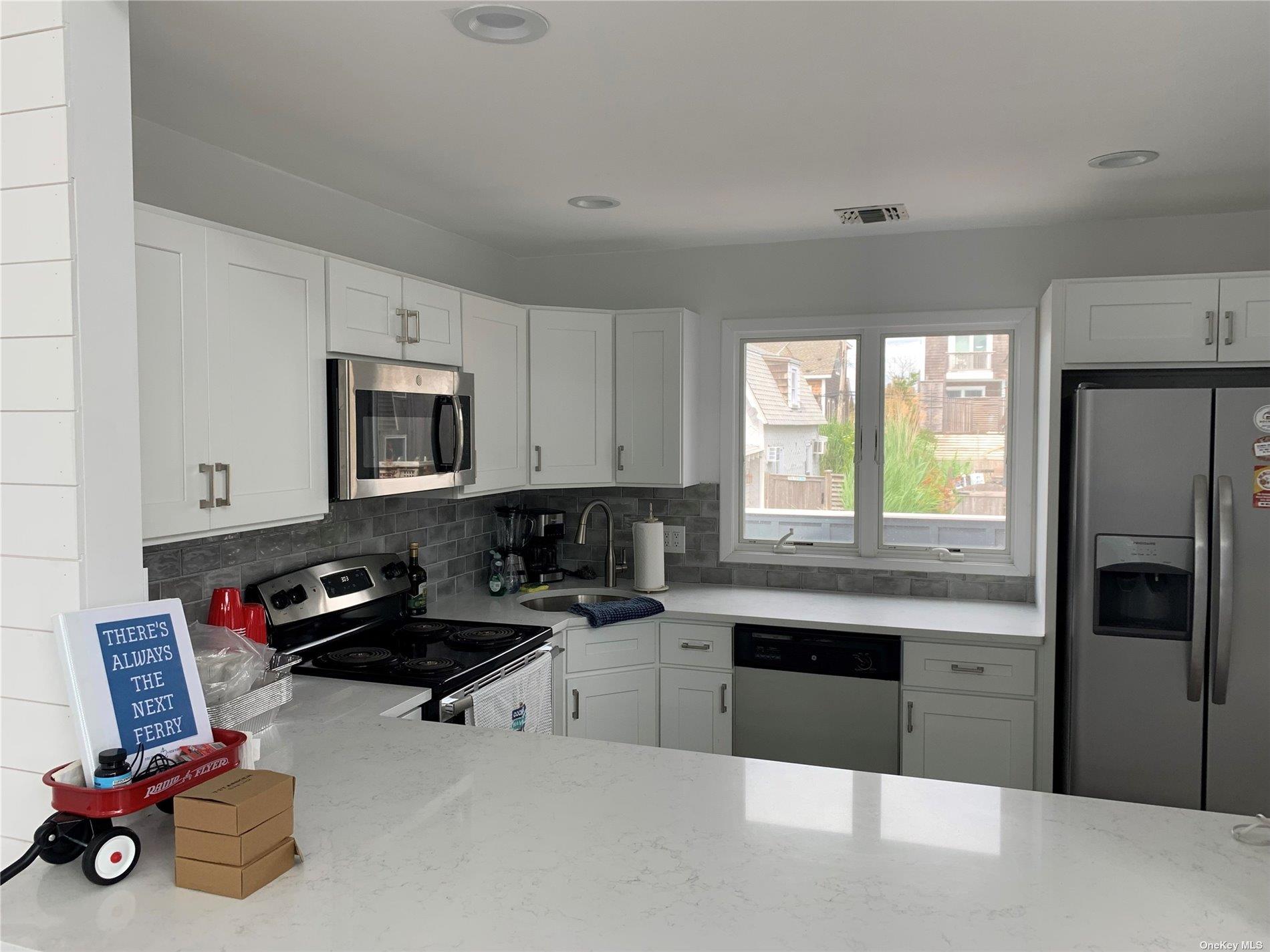 187 Cottage Walk Ocean Beach, NY 11770 - Photo 4 of 9 a kitchen with stainless steel appliances a sink a stove a refrigerator cabinets and a window