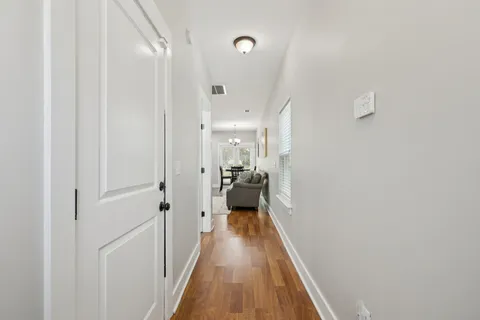 a view of a hallway with wooden floor and a bathroom