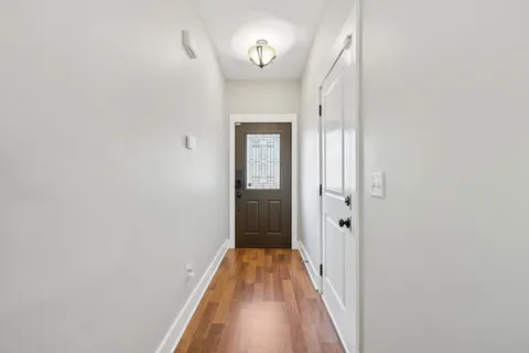 a view of a hallway with wooden floor and a door