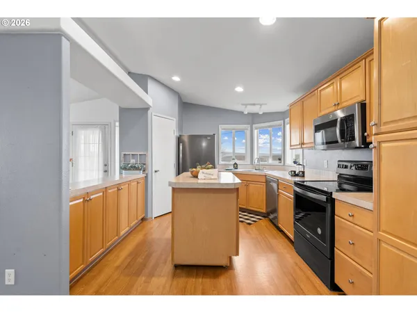 a large white kitchen with a sink and dishwasher a stove with wooden floor