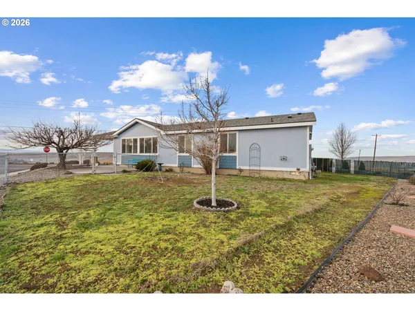 a view of a house with a big yard and large tree