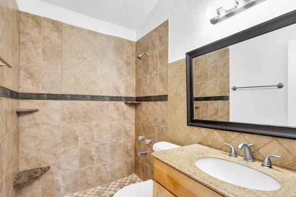 a bathroom with a granite countertop sink a mirror and a shower