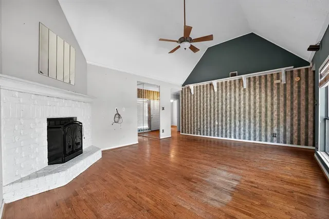 a view of an empty room with wooden floor and a fireplace