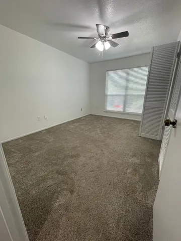 an empty room with a chandelier fan and windows
