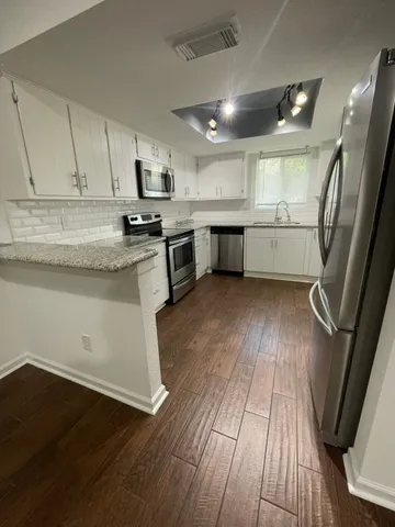 a kitchen with a sink wooden floor and stainless steel appliances