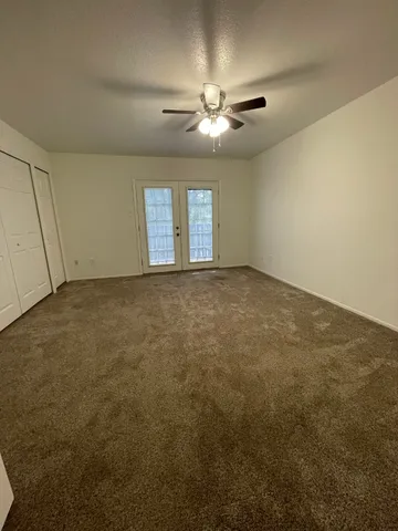 an empty room with windows and fan