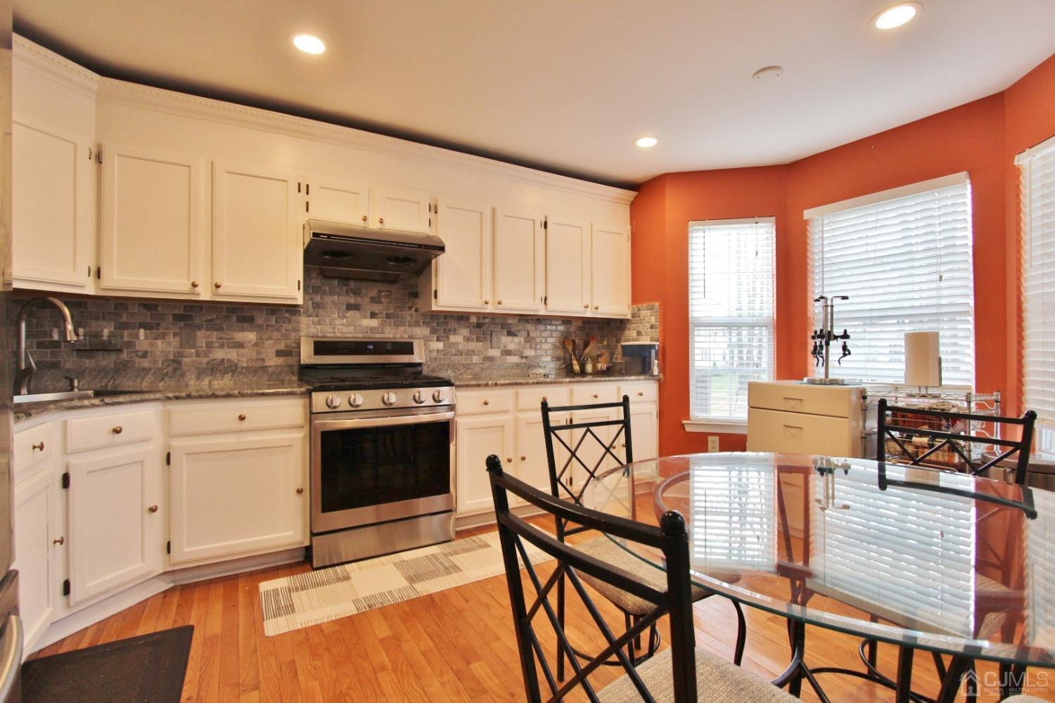 323 Hawthorne Road North Brunswick, NJ 08902 - Photo 8 of 29 a kitchen with stainless steel appliances granite countertop a stove top oven a sink a dining table and chairs with wooden floor