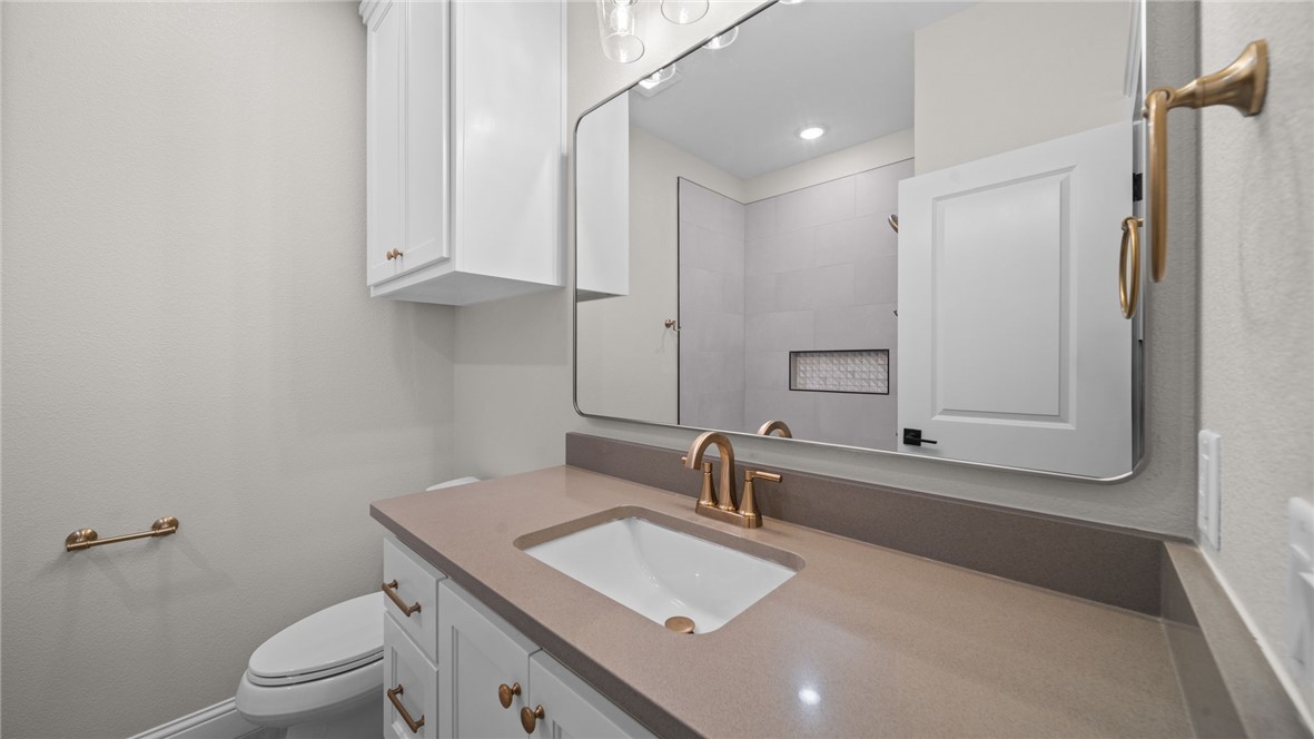 162 Buffalo Rdg Road Giddings, TX 78942 - Photo 24 of 31 a bathroom with a granite countertop sink a toilet and a mirror