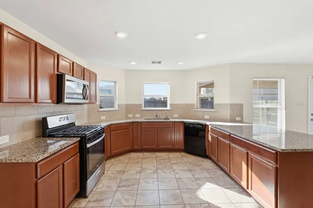 a large kitchen with stainless steel appliances granite countertop a stove sink and cabinets