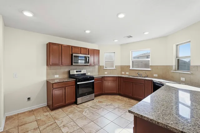 a kitchen with granite countertop a stove top oven microwave and cabinets