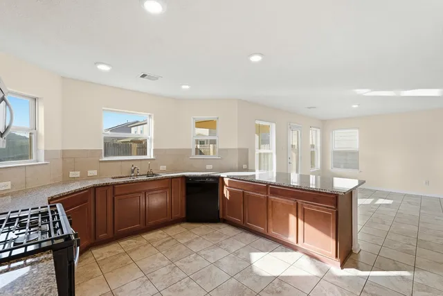 a large kitchen with stainless steel appliances granite countertop a sink and cabinets