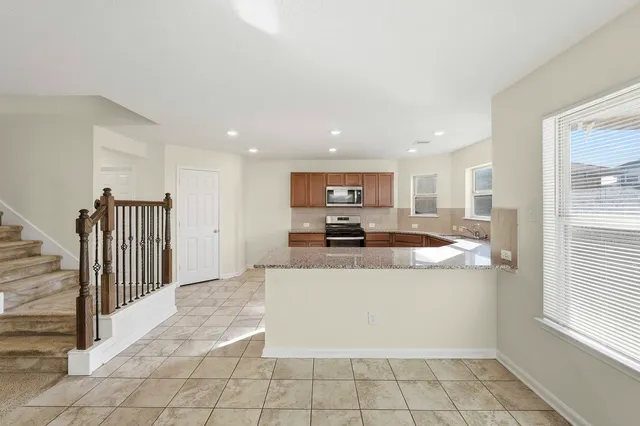 a living room with stainless steel appliances kitchen island granite countertop a refrigerator a stove and a sink