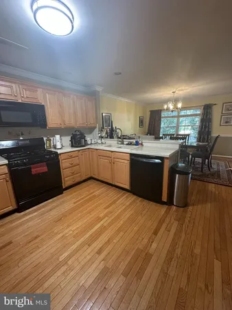 a kitchen with stainless steel appliances granite countertop a stove top oven a sink dishwasher and wooden cabinets with wooden floor
