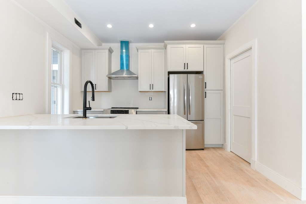 12 Ennis Road, Unit REAR Boston, MA 02119 - Photo 7 of 26 a kitchen with kitchen island a sink stainless steel appliances and cabinets