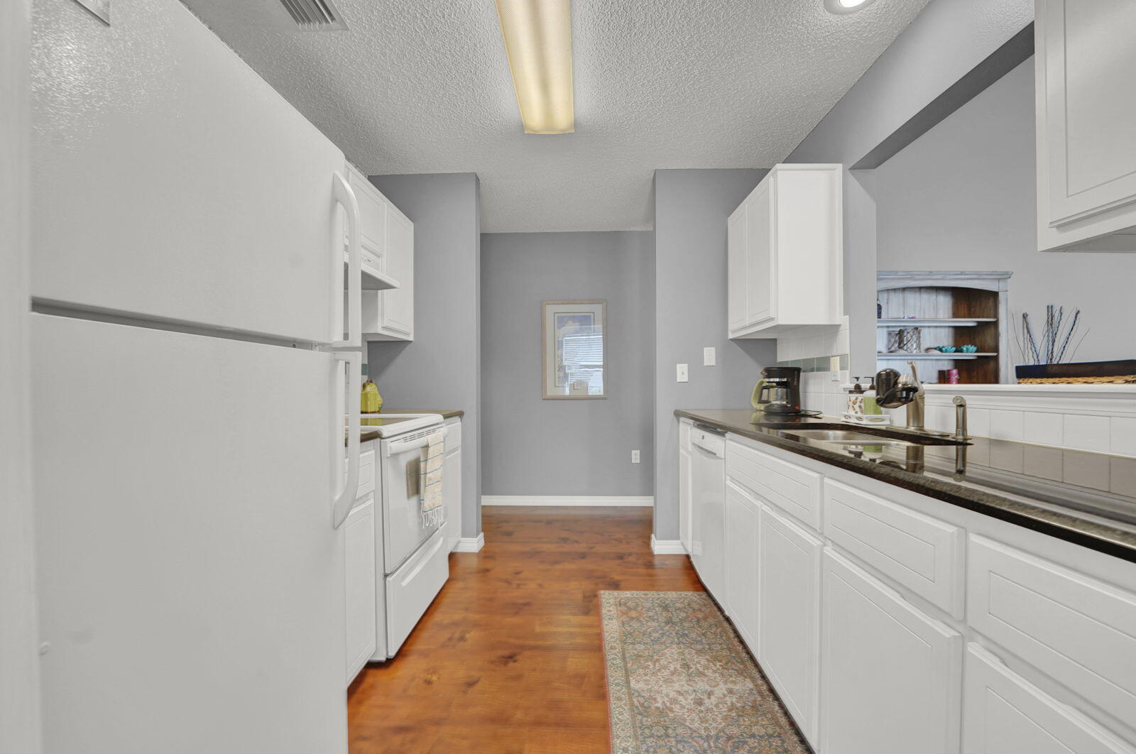 231 Vía Largo, Unit 39B Santa Rosa Beach, FL 32459 - Photo 13 of 50 a kitchen with white cabinets and white appliances