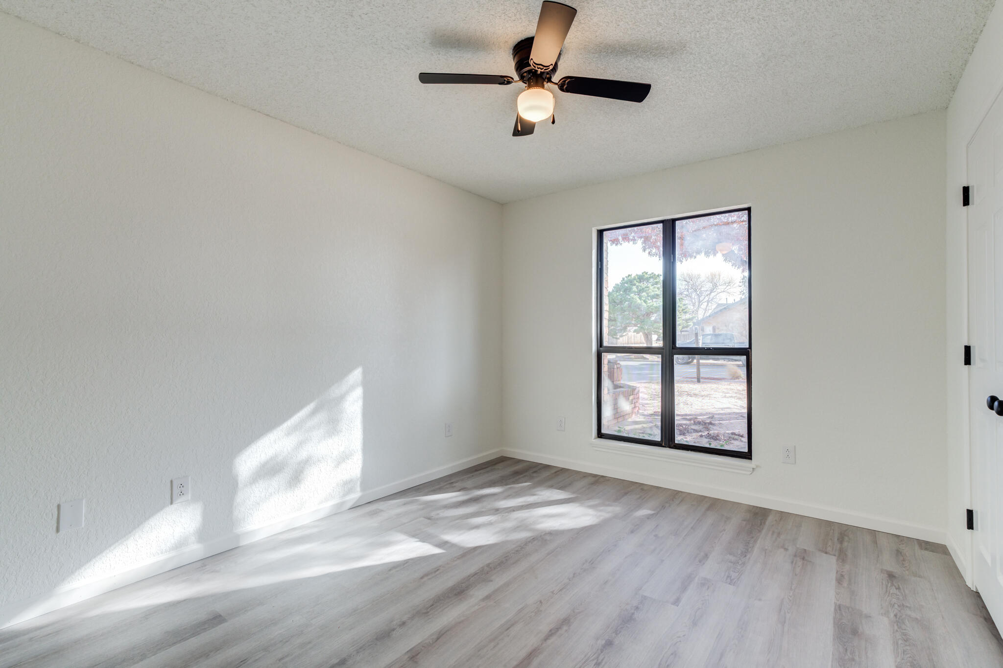3602 101st Street Lubbock, TX 79423 - Photo 36 of 51 an empty room with wooden floor ceiling fan and windows